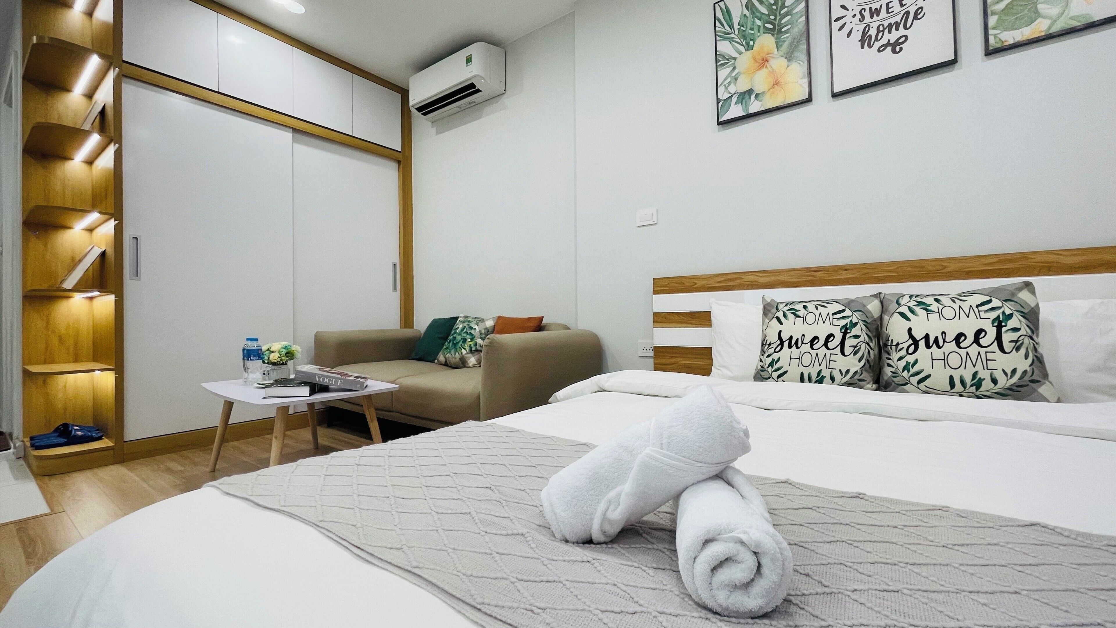 A neatly arranged bedroom with a bed, a bedside table, a sofa, and a wardrobe.