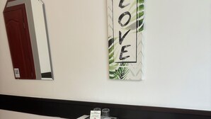 Een klein wit bureau met een grijze bank, een spiegel en een 'LOVE' bord op de muur.