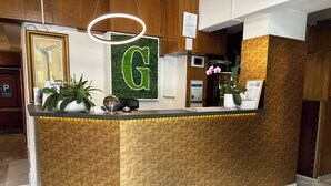 Een receptiebalie met een groot ‘G’ bord, een wereldbol en potplanten.
