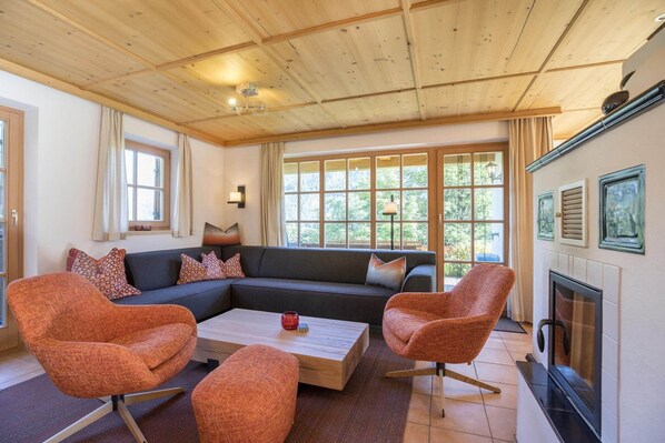 Een moderne woonkamer met een hoekbank, twee fauteuils, een salontafel en een open haard.