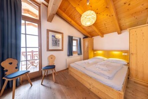 A wooden room with a bed, a chair, a window, and a picture on the wall. - Premium Mountain Chalet for 10 (Wald-Königsleiten)