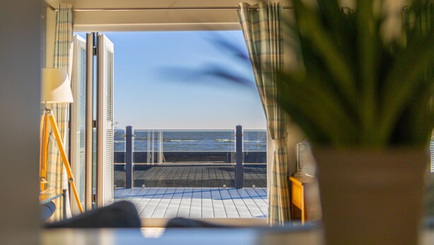 A balcony with a view of the sea, a potted plant, and a lamp. - The Great Escape - a frontline lodge overlooking Avon Beach (Mudeford)