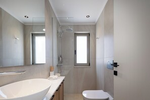 A modern bathroom with a large mirror, a white sink, a toilet, and a shower area. - Imbros Villas Free* Heated Pools in mountains! (Crete)