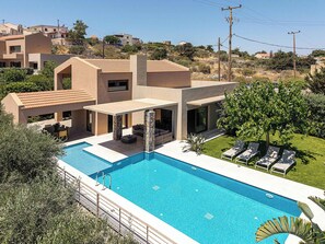 Een modern huis met een zwembad, terras en uitzicht op de omgeving.