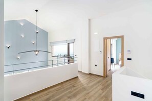Een modern interieur met een glazen balustrade, een trap en uitzicht door een raam.