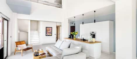 Un salón amplio con un sofá, una mesa de centro y un comedor con cocina al fondo.