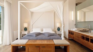 A bedroom with a canopy bed, bedside tables with lamps, a wooden bench, and a large mirror above the vanity. - Adeste Seaview Villas Double - 2 Pools,900m to sea (Chania)