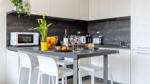 A modern kitchen with a microwave, a potted plant, a wine bottle, and a fruit bowl.
