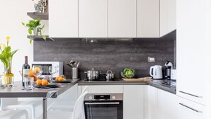 A modern kitchen with white cabinets, a built-in oven, and a countertop with various appliances and fresh produce.