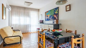 A compact living space with a dining table, chairs, a sofa, and a large painting.
