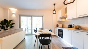 Una cocina moderna con armarios blancos, una mesa de comedor con sillas y un ventanal grande.