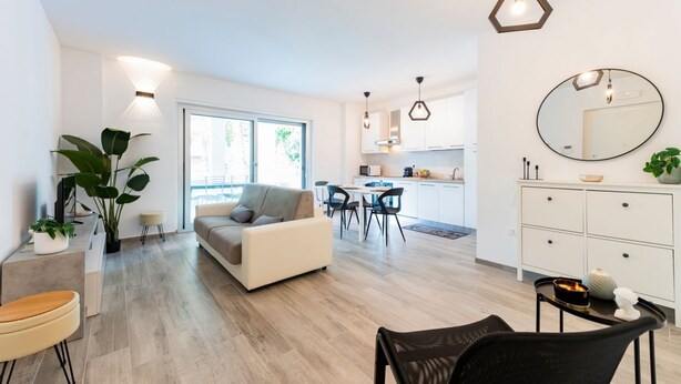 Una sala de estar moderna con sofá, comedor, cocina y un gran ventanal.