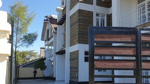 A residential building with a gated entrance, a staircase, and a clear sky.