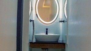 A bathroom with a round mirror, a sink, and a towel rack.