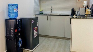 A compact kitchen with white cabinets, a sink, and a water dispenser.