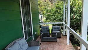 Une terrasse couverte, aménagée avec des meubles en osier, un sol en briques et un mur végétal.