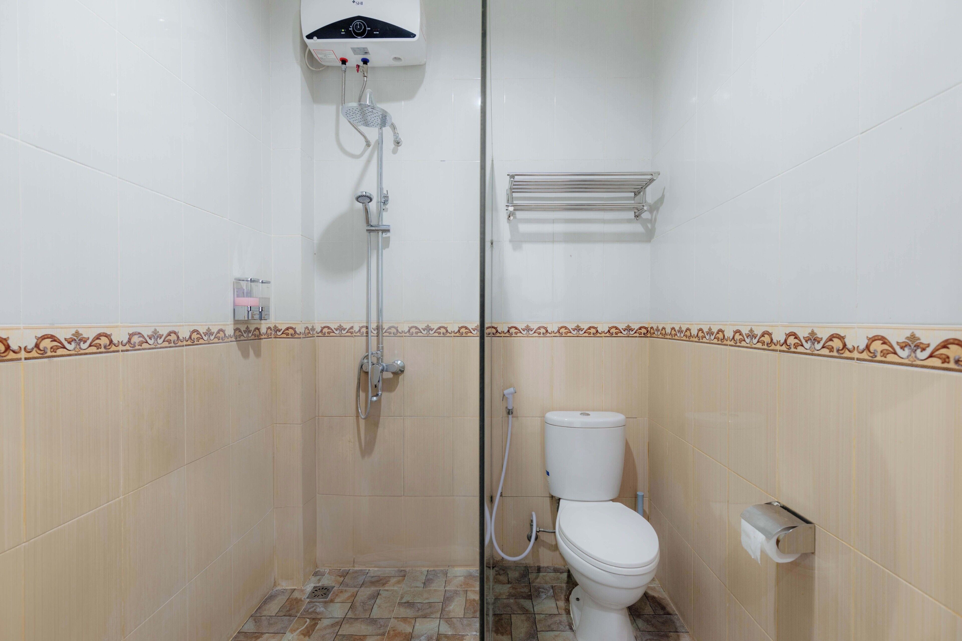Une salle de bain équipée d’une douche, de toilettes et d’un porte-serviettes.