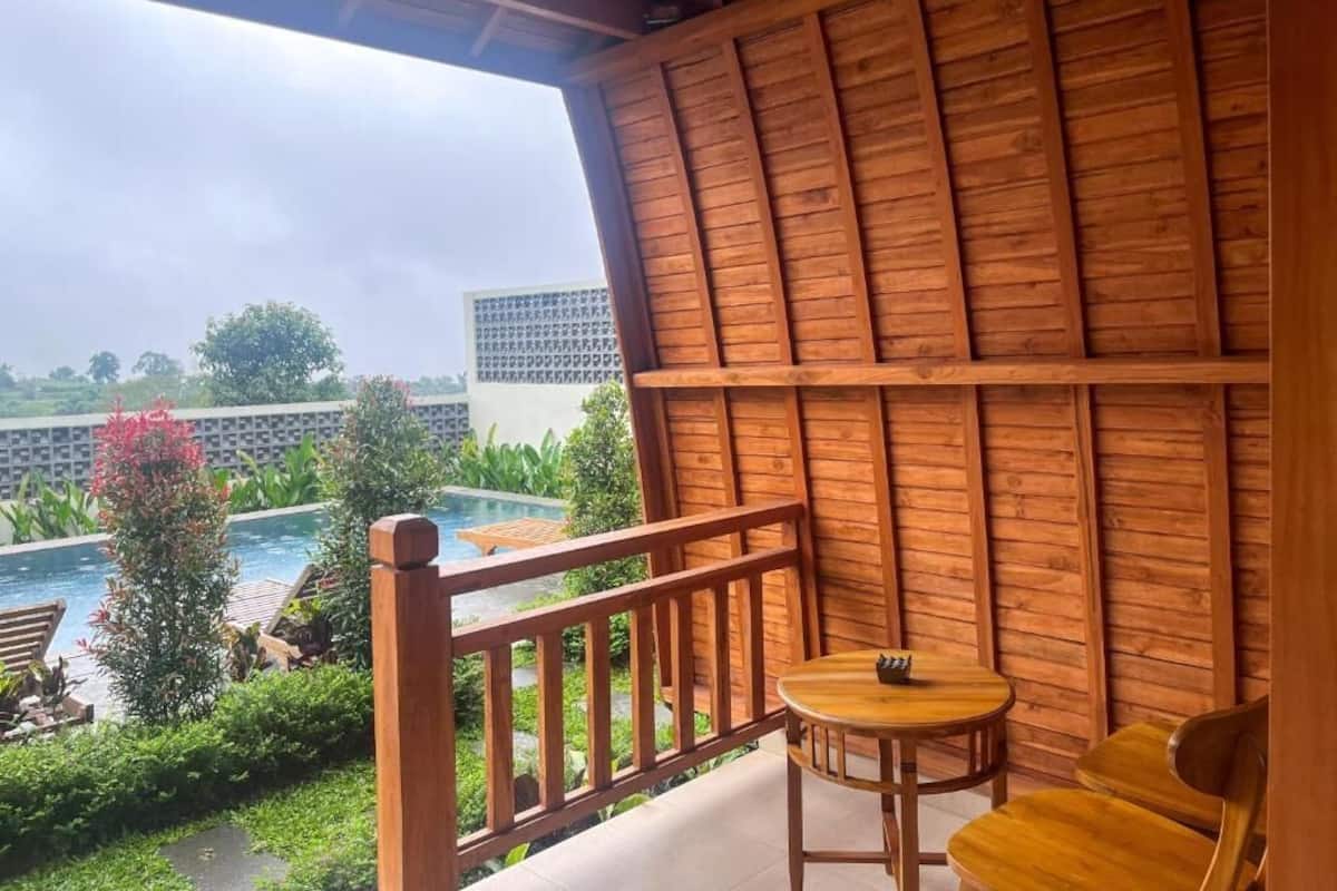 Ein Holzbalkon mit Blick auf einen Pool und Grünflächen.