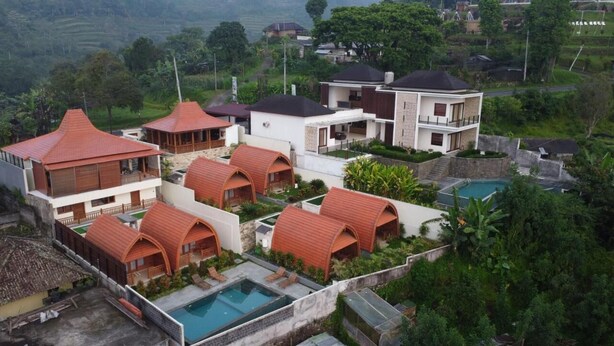 Un resort con múltiples alojamientos tipo bungaló, piscina y exuberante vegetación que rodea la propiedad.