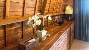 Un mostrador de recepción de madera con una orquídea en maceta, una lámpara y una cesta.