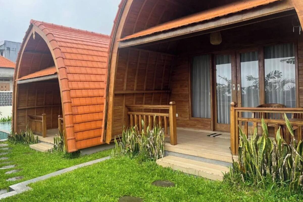Eine Holzhütte mit einem Rundbogen-Dach, einer Holzterrasse und einem Poolbereich.