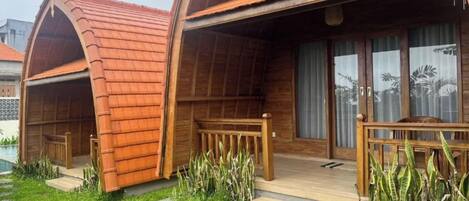 A wooden cabin with an arched roof, a wooden deck, and a pool area.