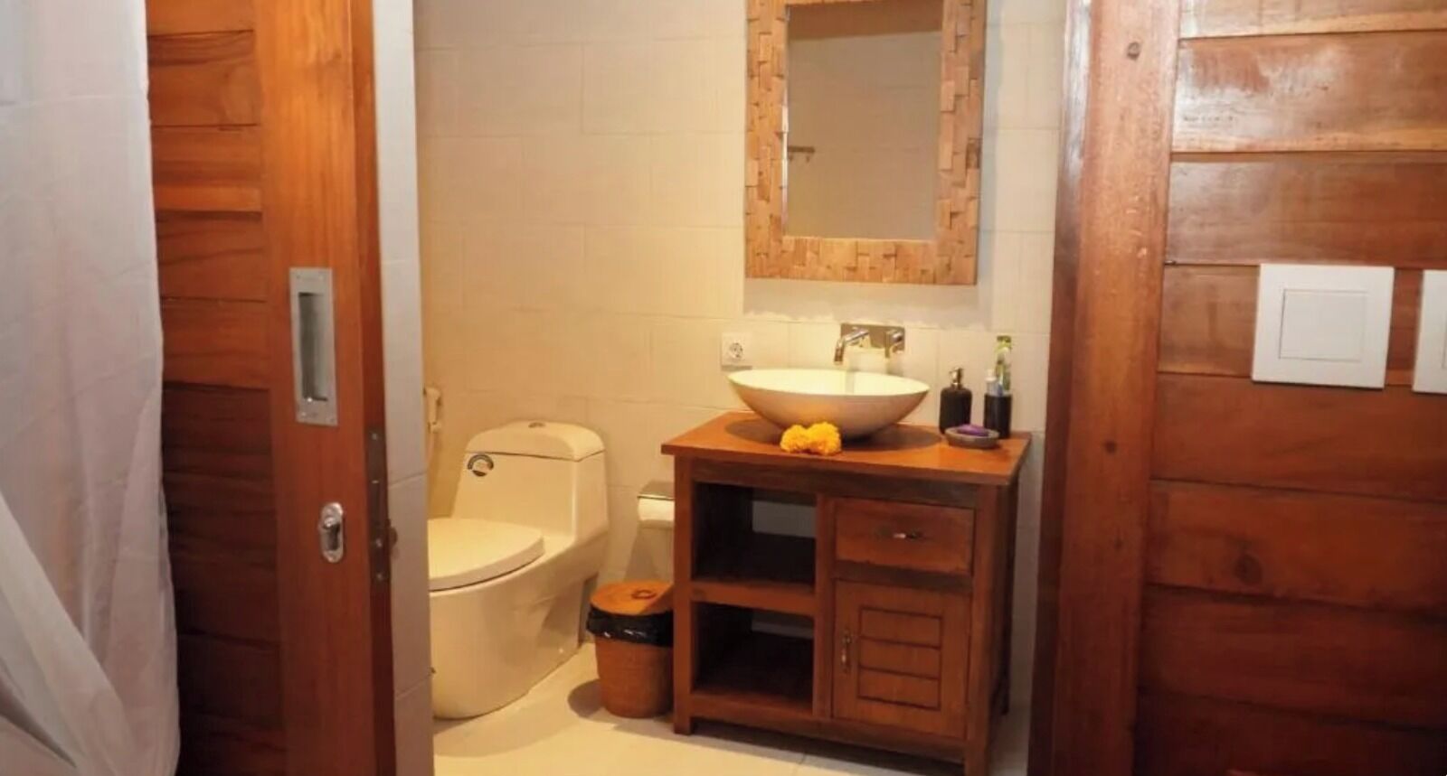A bathroom with a wooden vanity, a white sink, and a toilet.