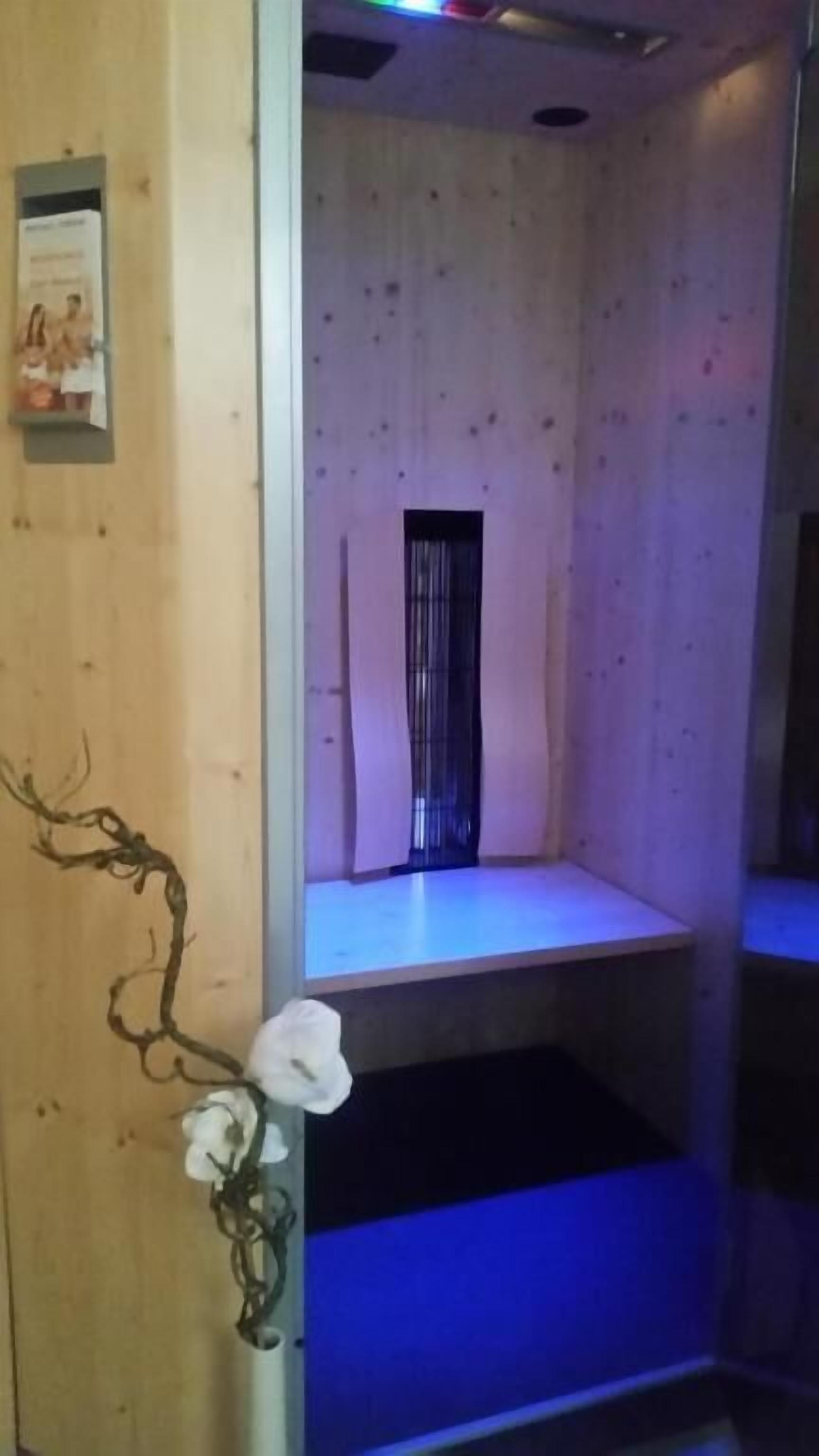 Une pièce aux murs en bois, avec une petite fenêtre et une étagère illuminée d’une lumière bleue.