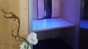 Une pièce aux murs en bois, avec une petite fenêtre et une étagère illuminée d’une lumière bleue.