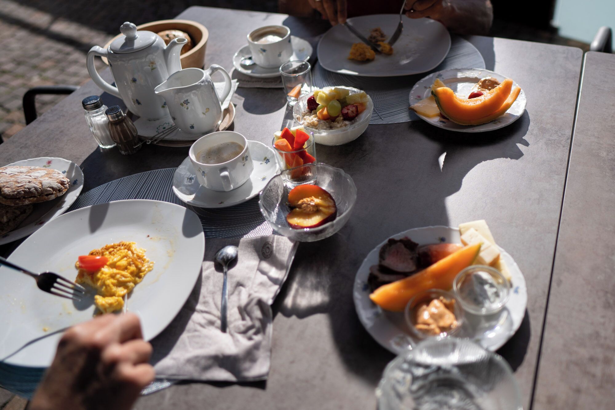 Une table dressée avec des aliments pour le petit-déjeuner, notamment des œufs, des toasts, des fruits et du café.