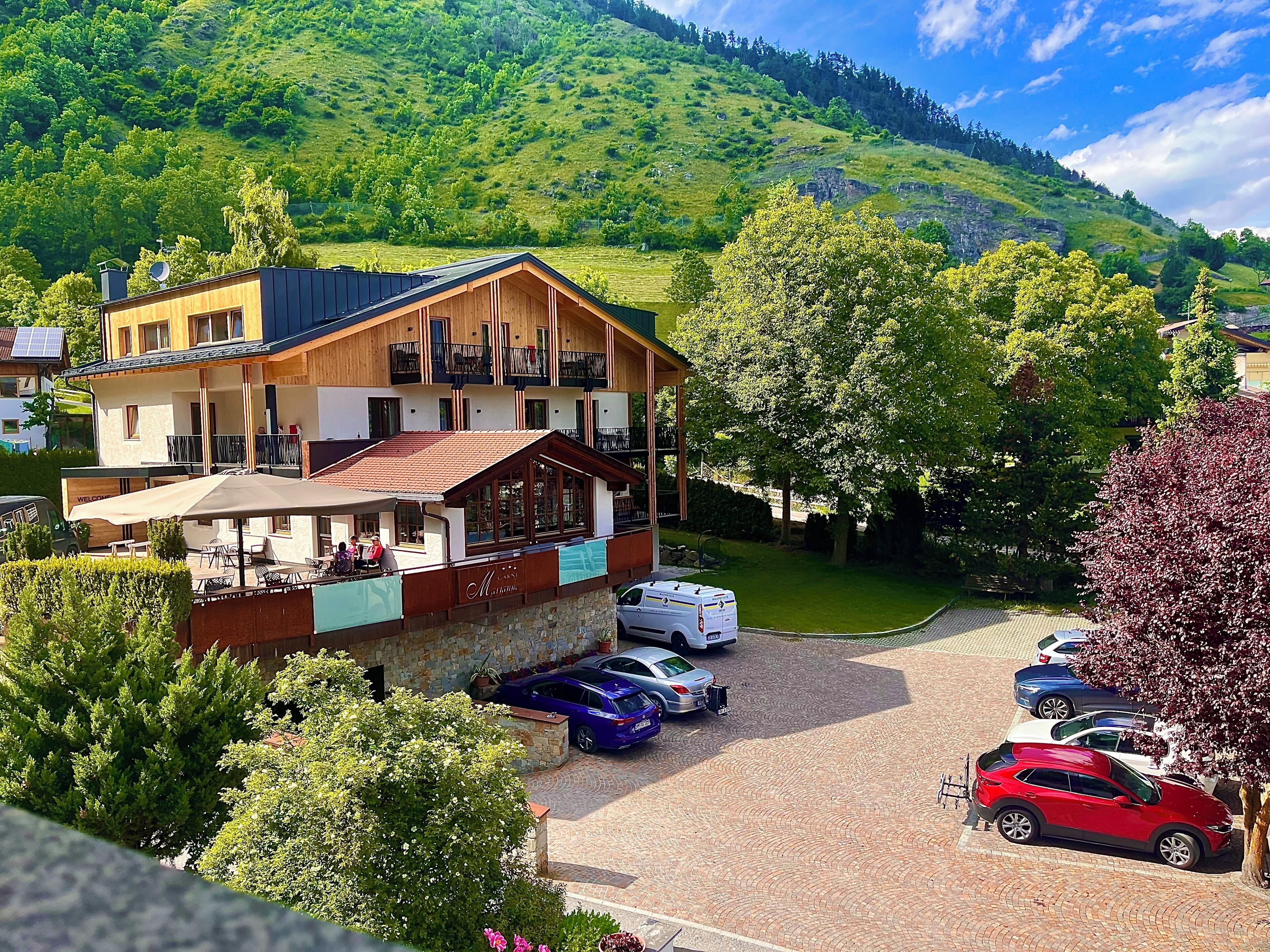 Un hotel con fachada de madera, balcones y un estacionamiento con coches.