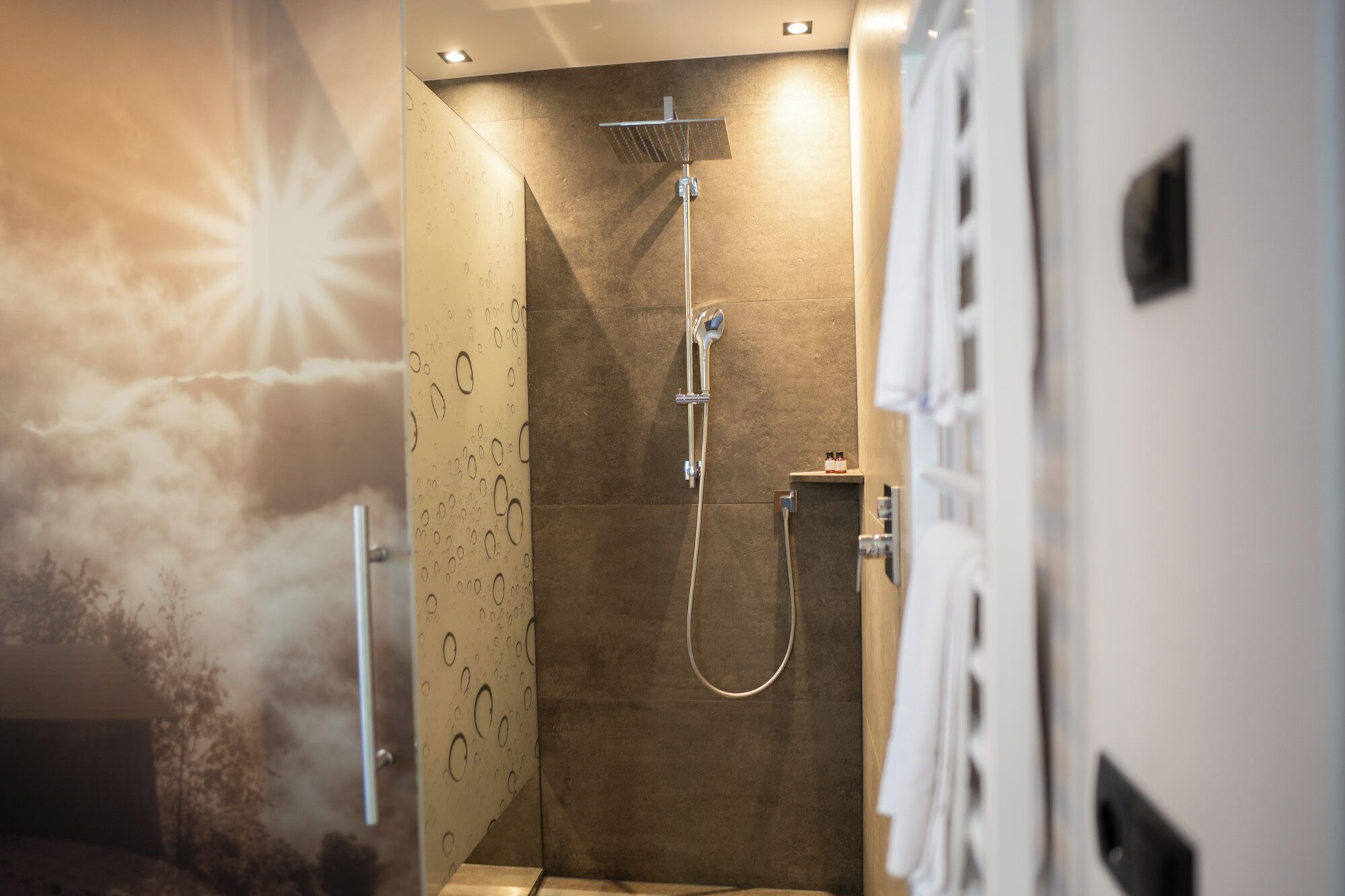Eine moderne Dusche mit Glastür, Handbrause und einer fest montierten Bedienarmatur.