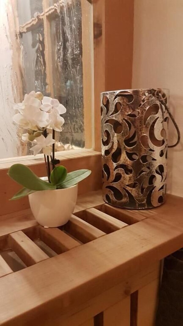 Een houten bank met een potorkidee en een decoratieve metalen vaas.