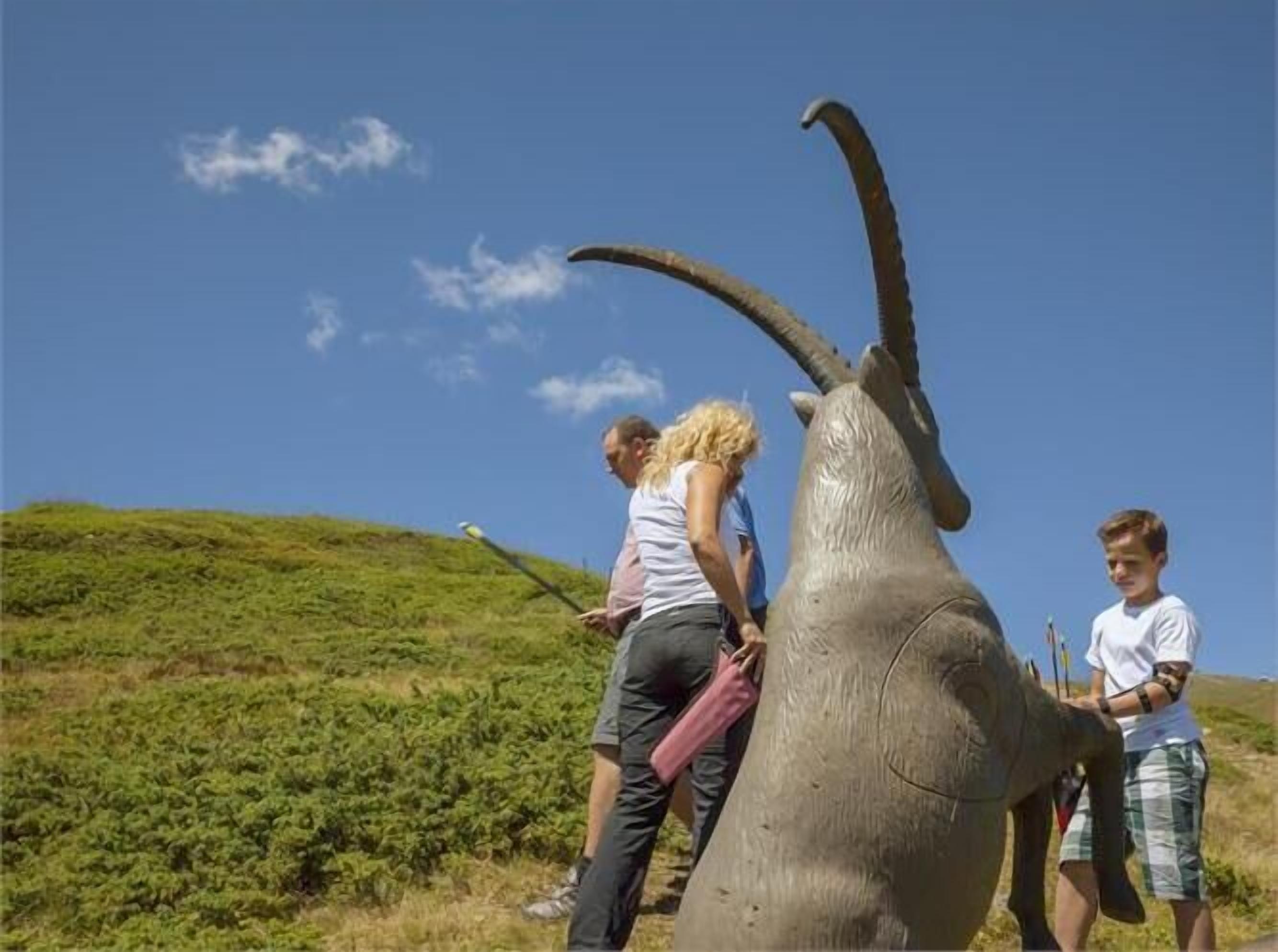 A large sculpture of a goat with people standing around it.