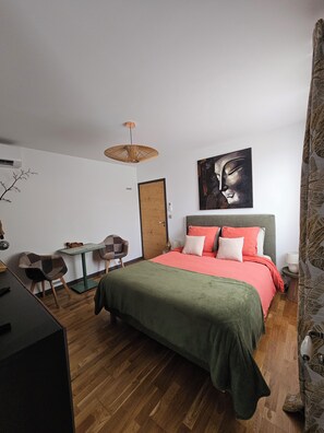 Un dormitorio con cama, escritorio, silla, lámpara colgante y una puerta.