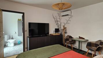 A modern hotel room with a large bed, a television, a desk, and a chair.