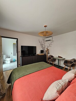 Una habitación de hotel moderna con una cama grande, televisor, escritorio y una silla.