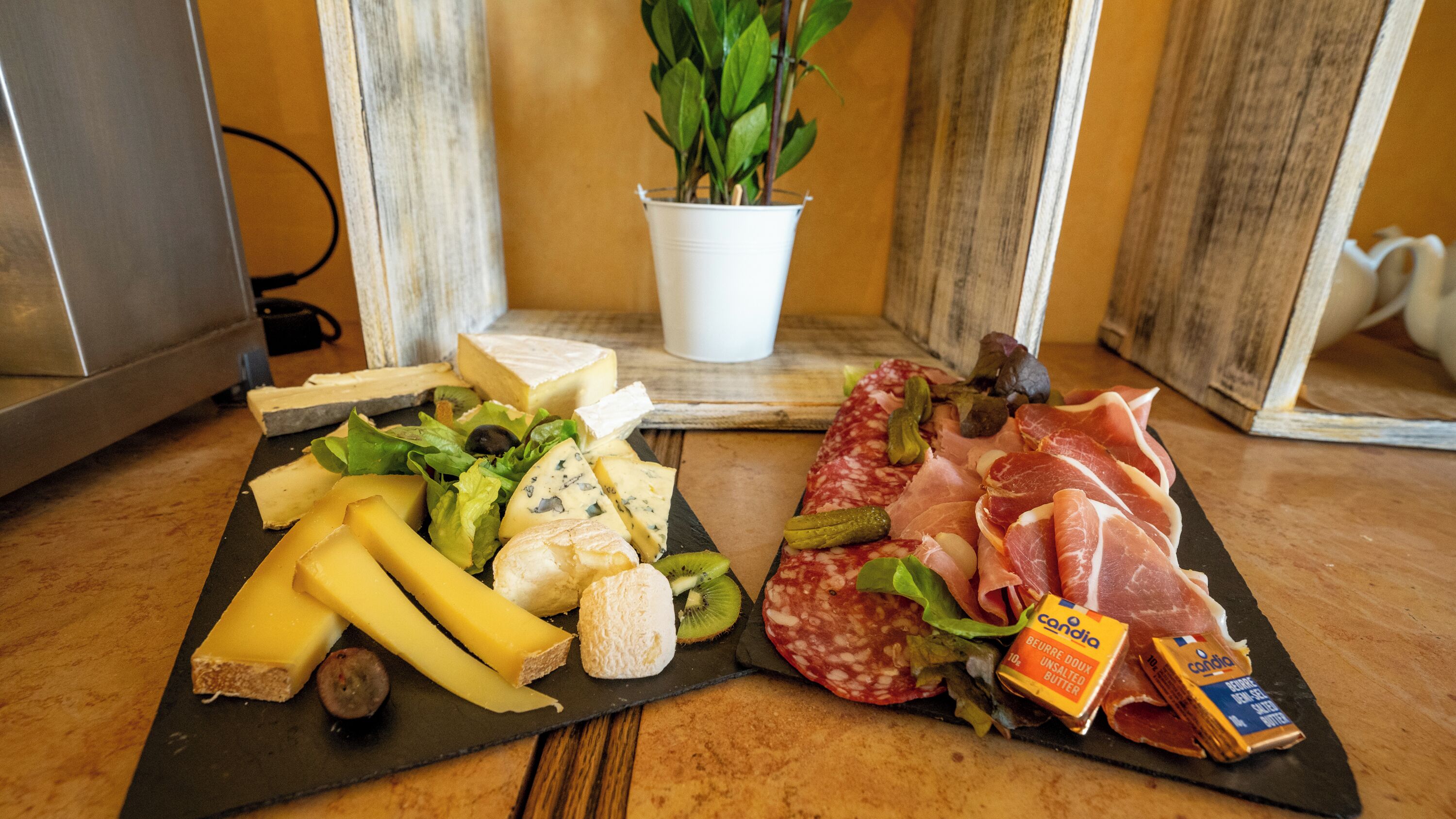 Une planche de charcuterie comprenant divers fromages, viandes et cornichons, présentée sur une ardoise.