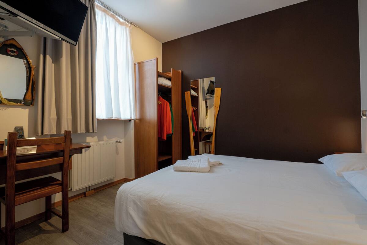 Une chambre d’hôtel comprenant un lit, un bureau, une chaise, une armoire et un miroir.