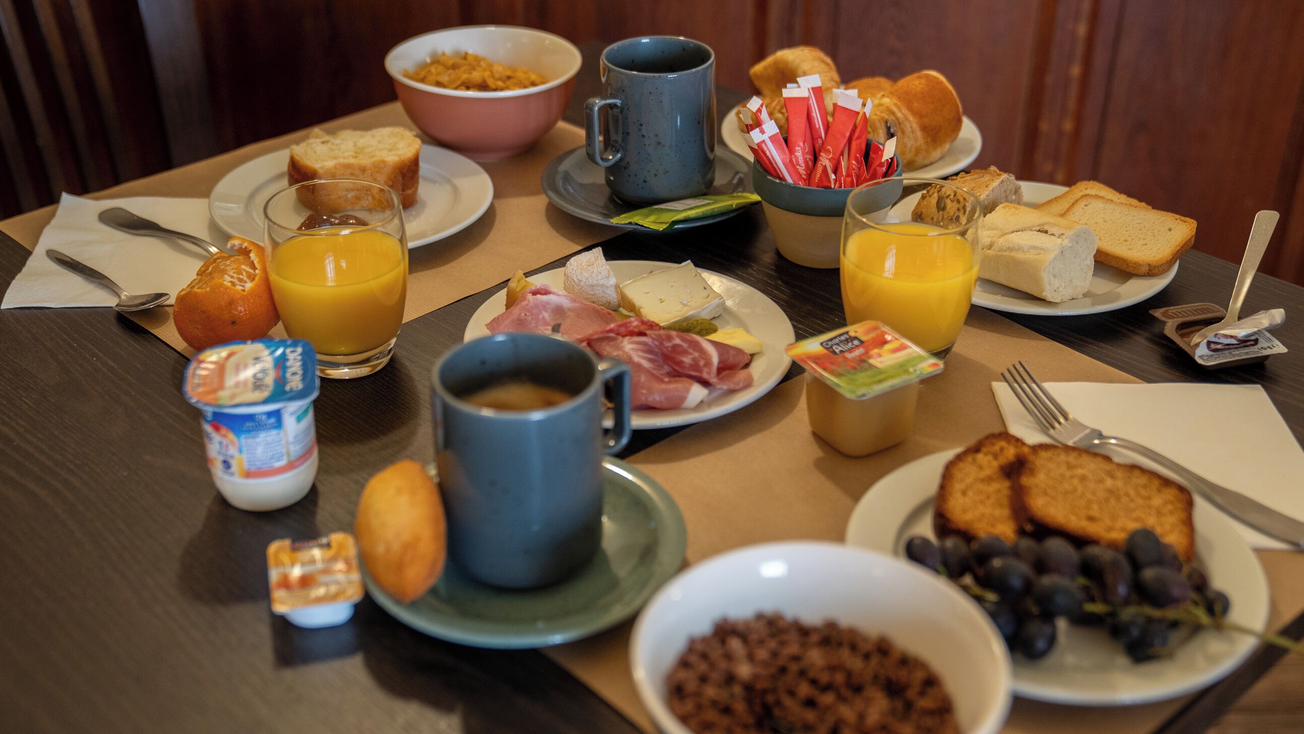 A breakfast table with various food items and drinks.