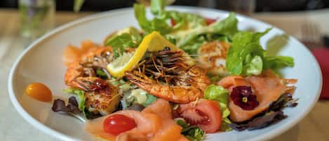 Un plato de comida con camarones, salmón y verduras.