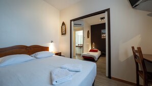 Een hotelkamer met een bed, een bureau en een stoel. Een badkamer is zichtbaar door een geopende deur.