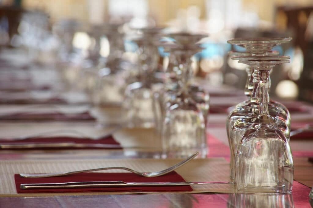 A dining table with clear glassware and a red menu.