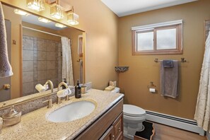 A bathroom with a large mirror, a sink with a vanity, a toilet, and a window with a towel hanging on the wall. - Walking Distance to Downtown Bozeman (Bozeman)