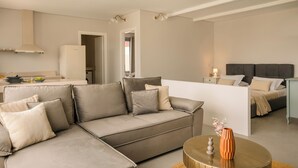 Uma sala de estar moderna com um sofá, uma mesa de centro e uma cama ao fundo.