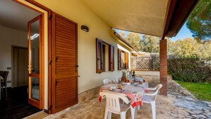 Eine Terrasse mit Steinboden, einem Tisch gedeckt mit Tellern und Gläsern sowie einer Holztür.