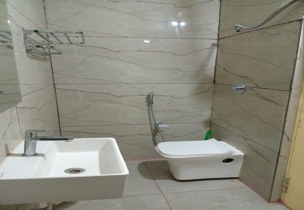 A bathroom with a white sink, a toilet, and a shower area. - Grand Inn (Tiruvannamalai)