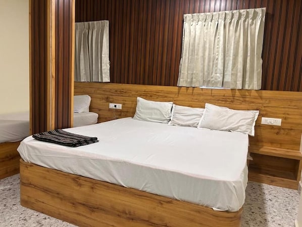 A wooden bed with white linens, a wooden headboard, and a mirror above it. - Grand Inn (Tiruvannamalai)