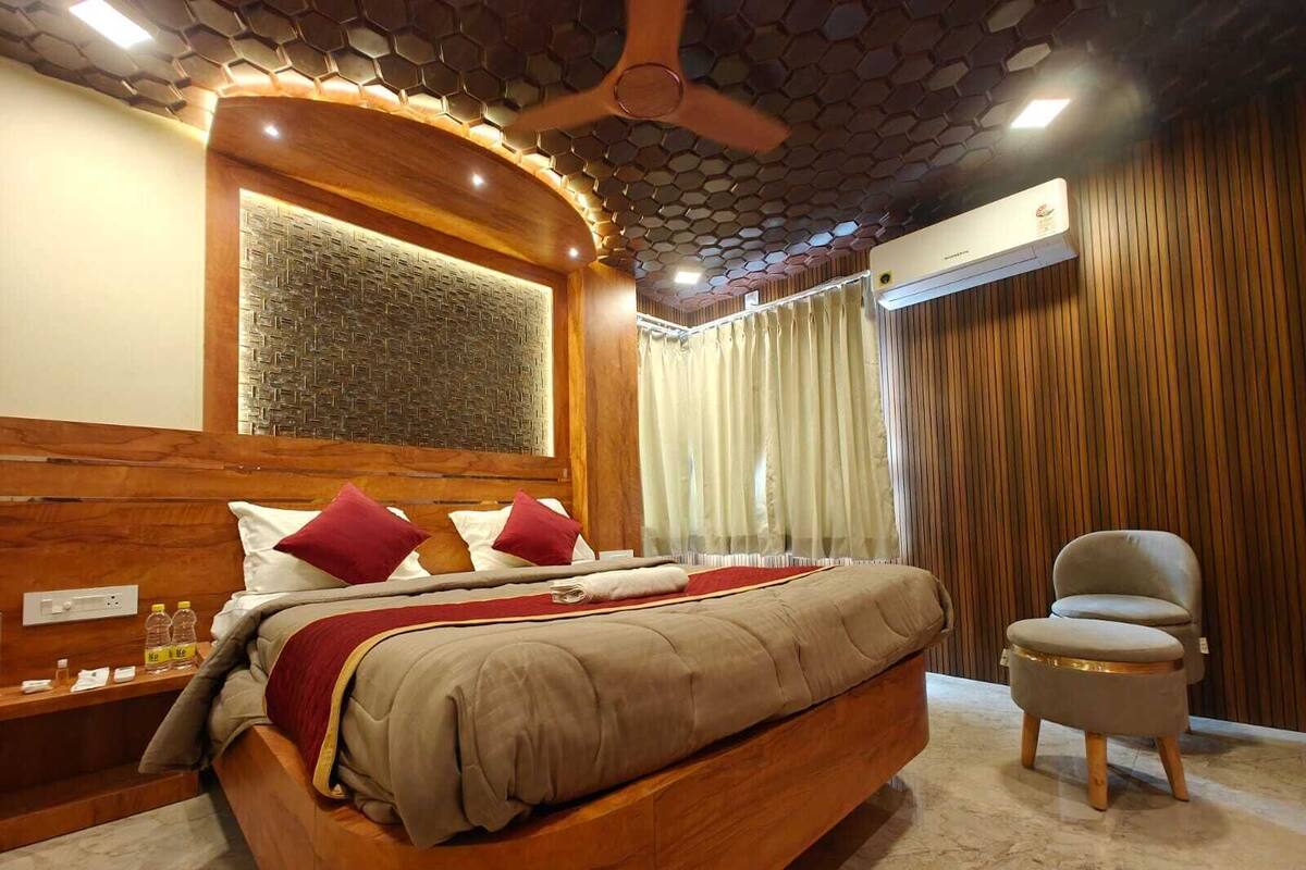 Un dormitorio moderno con cama de madera, ventilador de techo y un amplio ventanal con cortinas.