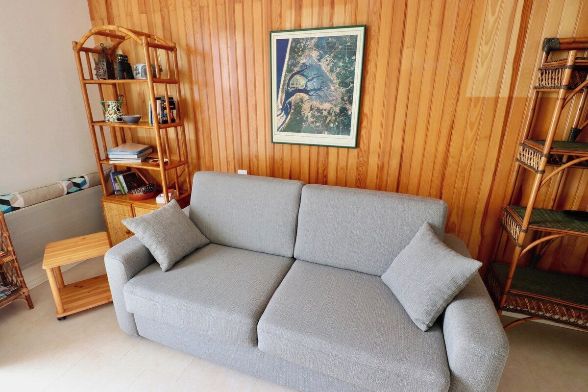 A living room with a grey sofa, a wooden bookshelf, and a framed picture on the wall.